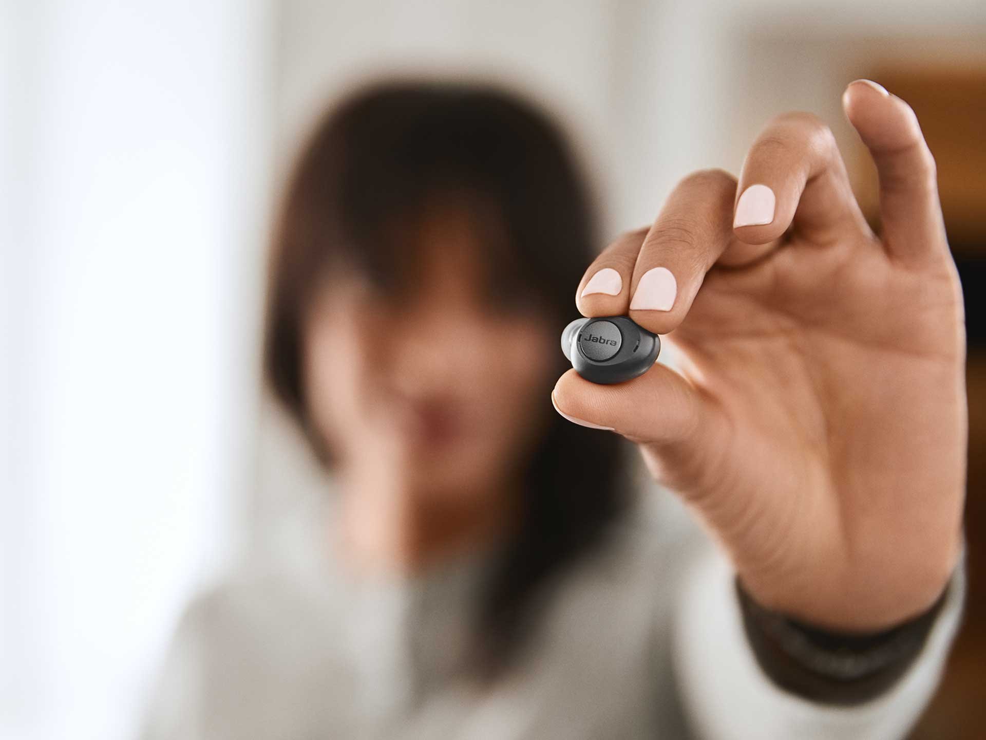 Person holding a bluetooth ear bud
