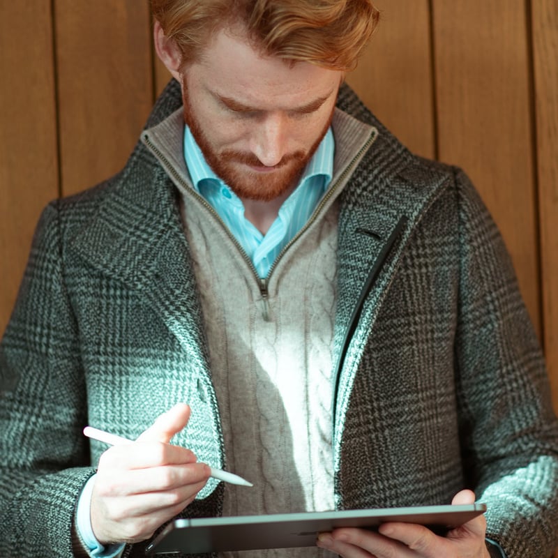En mann med rutete frakk ser ned på en iPad