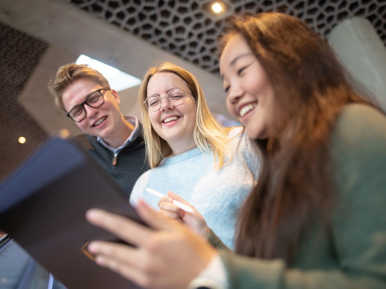 Tre mennesker står og ser ned på en iPad