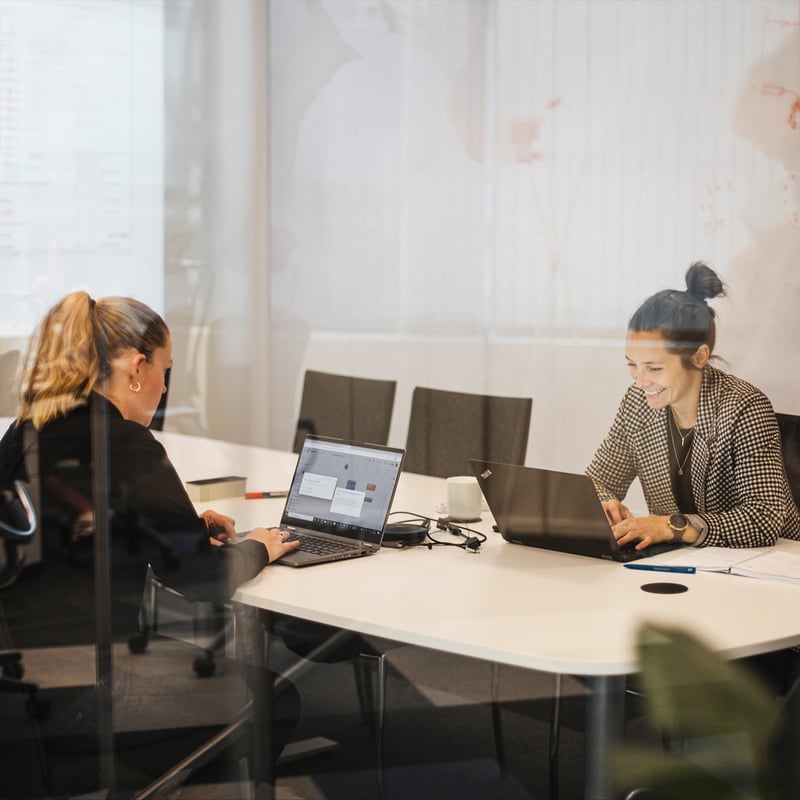 To damer sitte på hver sin PC på et kontor