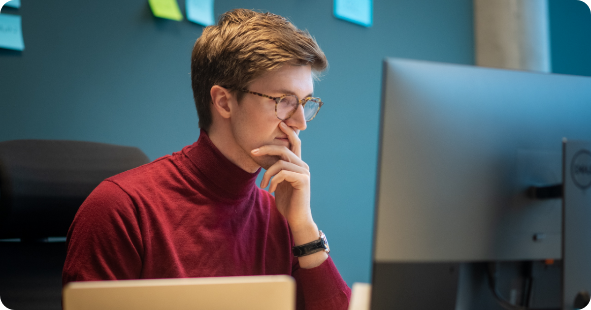 Mann sitter og ser på en pc-skjerm