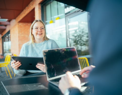 Bilde av en dame forfra som prater mens hun har en ipad i hånden