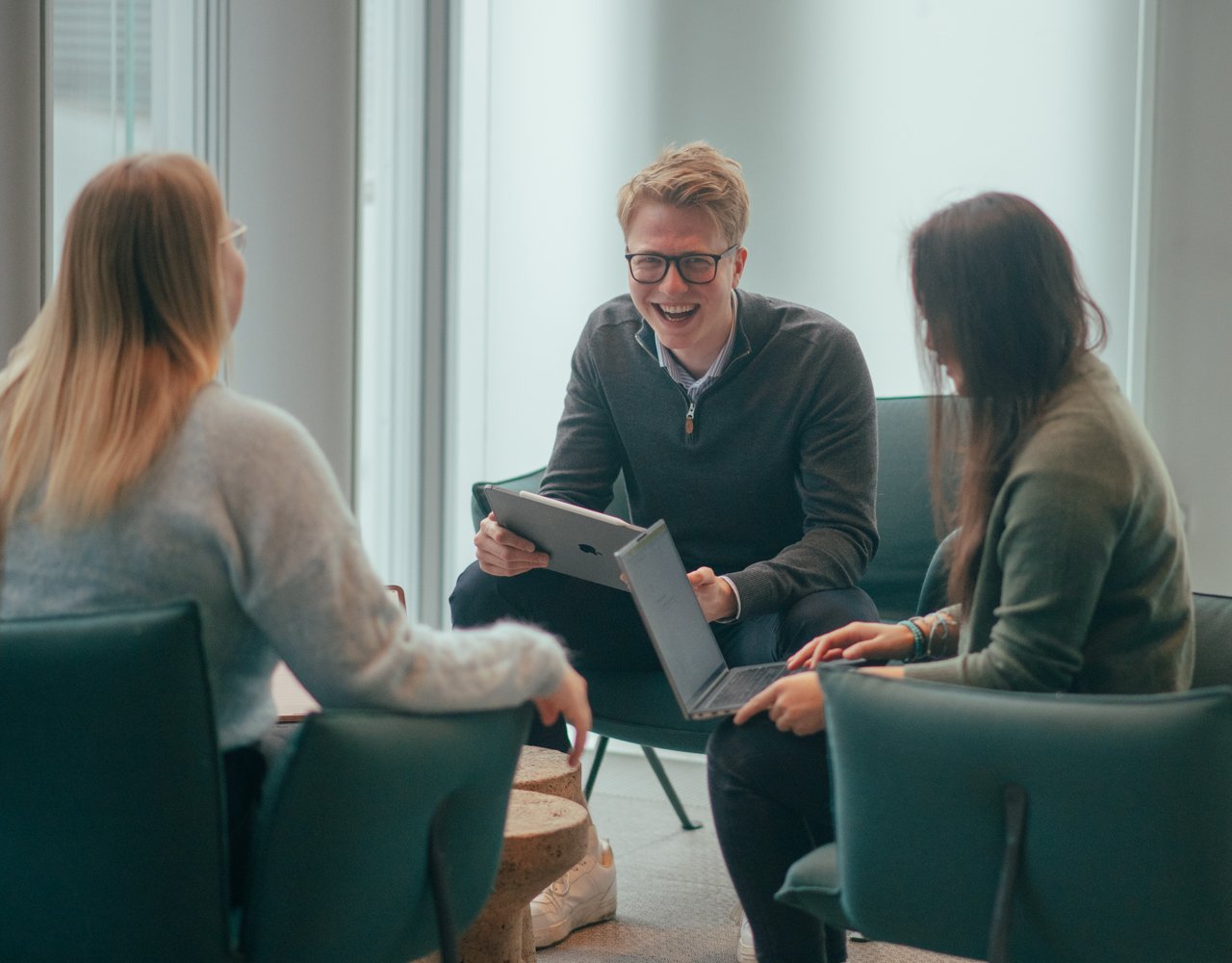 Bilde av to damer og en mann som sitter i en sittegruppe og prater om business intelligence