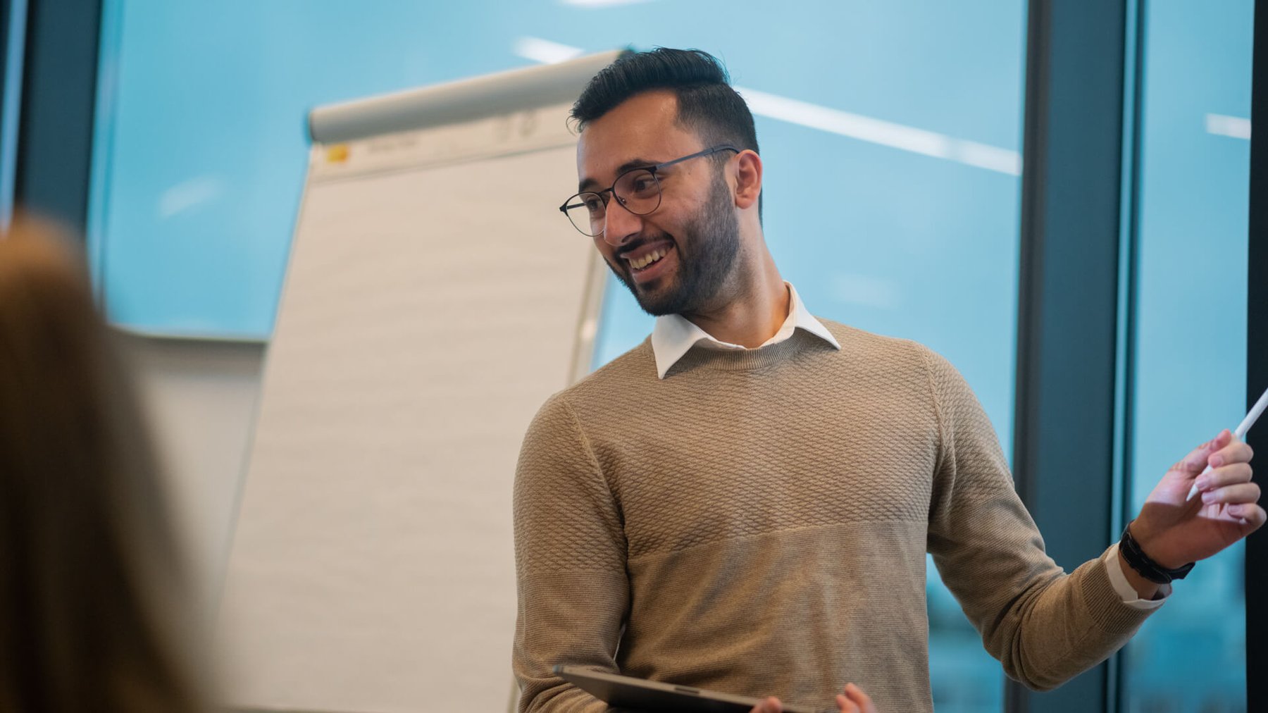 Bilde av en mann som står og smiler og peker i et møterom