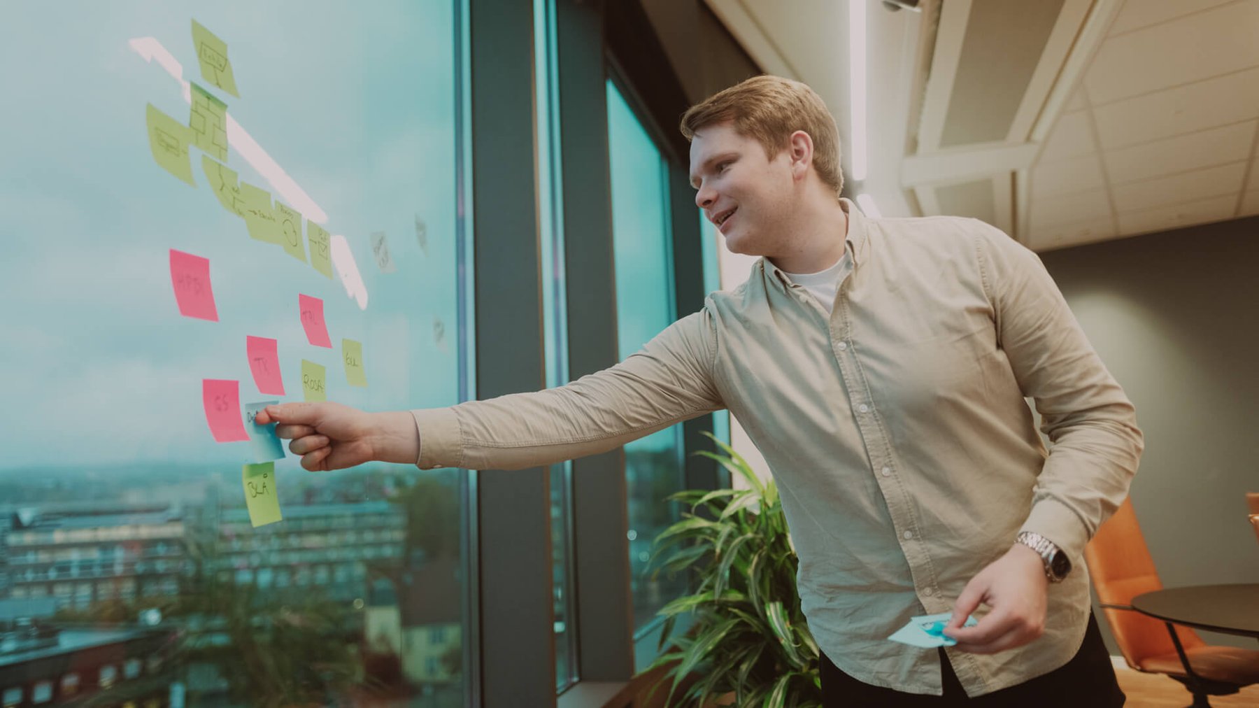 Mann peker på postitlapper som henger på et vindu