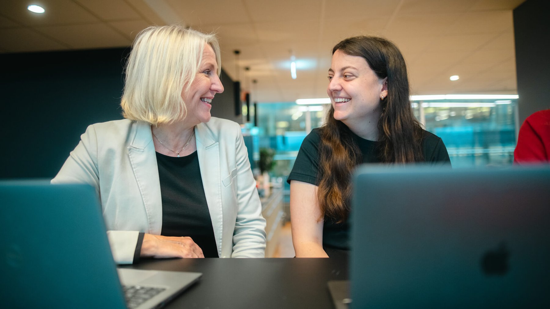 To kvinnelige kollegaer sitter sammen og smiler