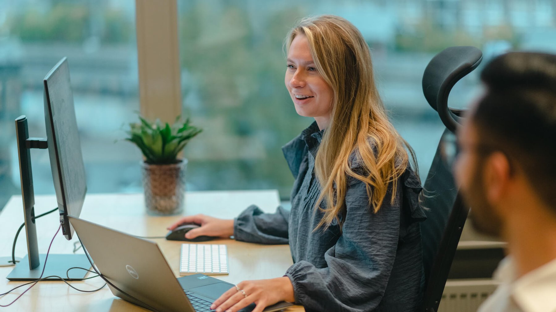 Ung dame jobber på en PC mens hun smiler og ler