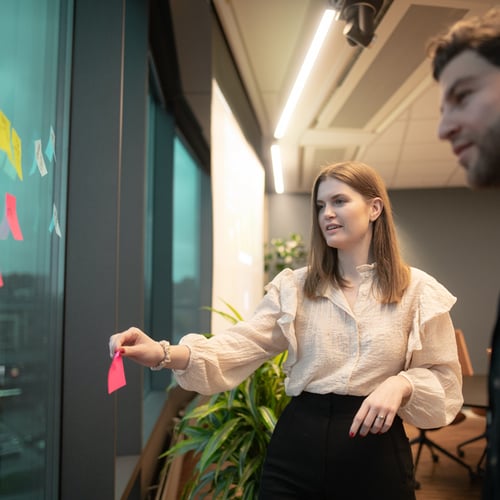 Bilde av mann og dame som henger opp postit lapper på et vindu