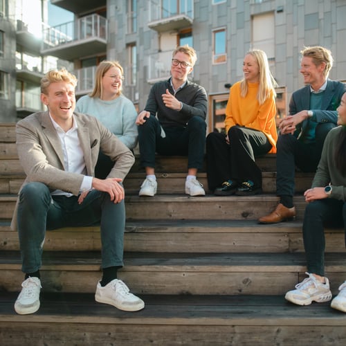 En gruppe mennesker sitter ute i en trapp og ler og smiler