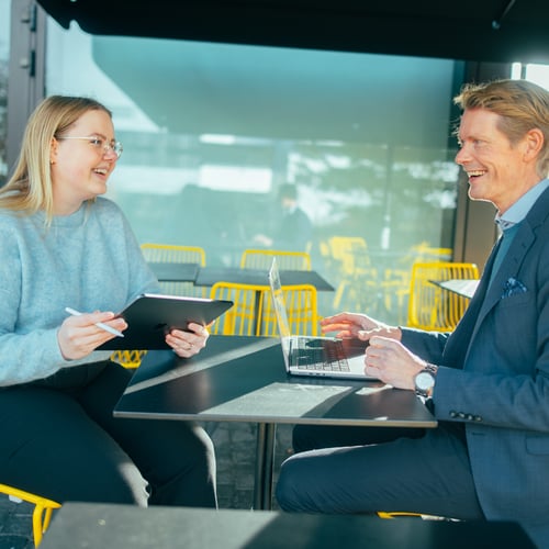 En mann og en dame sitter på en kafe og prater mens de jobber