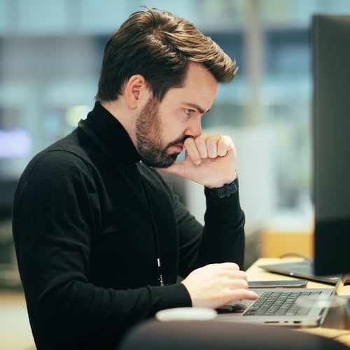 Portrett av en mann som sitter foran en PC og ser konsentrert ut