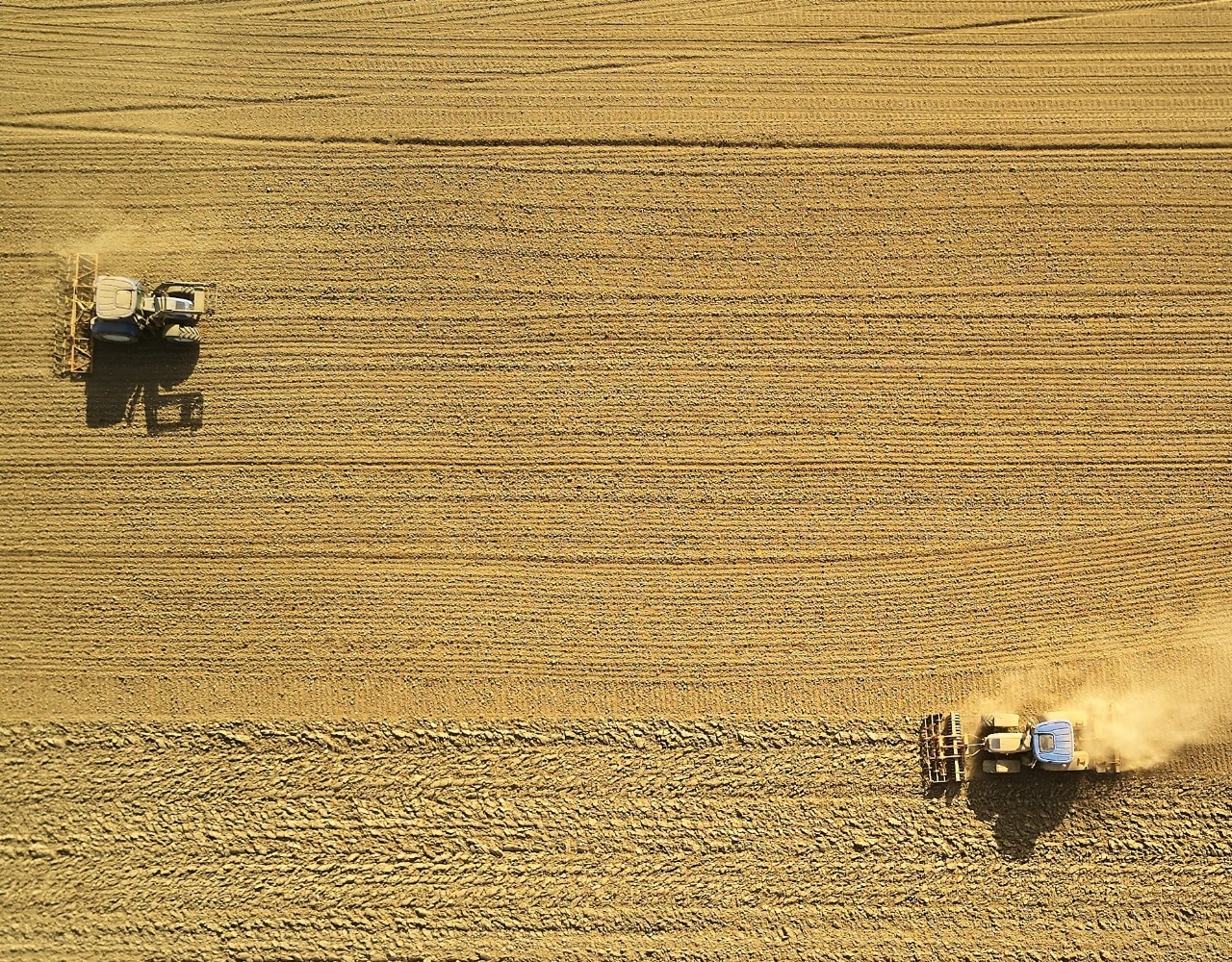 Bilde av to traktorer som kjører på et jorde