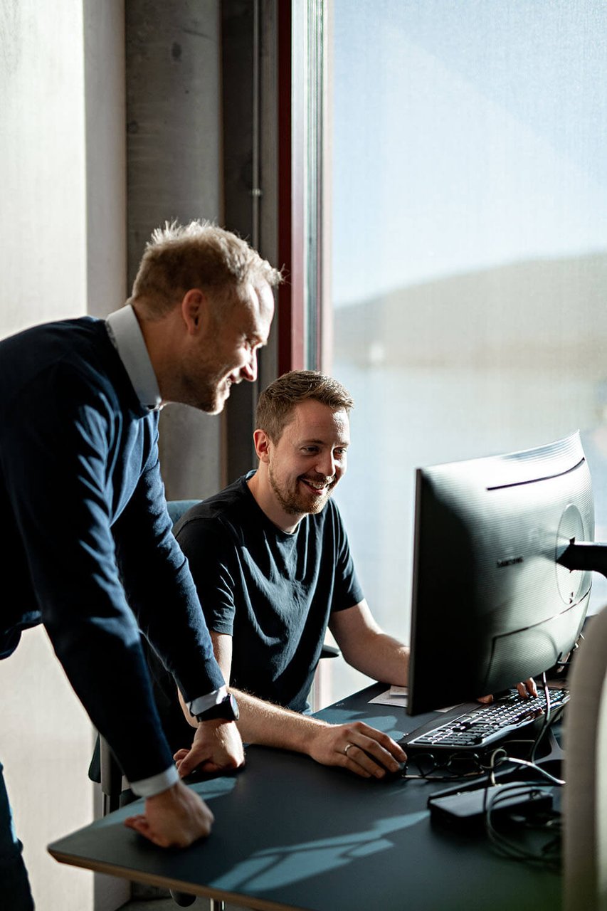 To kolleger som jobber sammen, foran skjermen til den ene