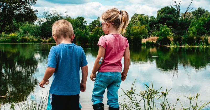 To barn står med ryggen til og ser utover en stor elv