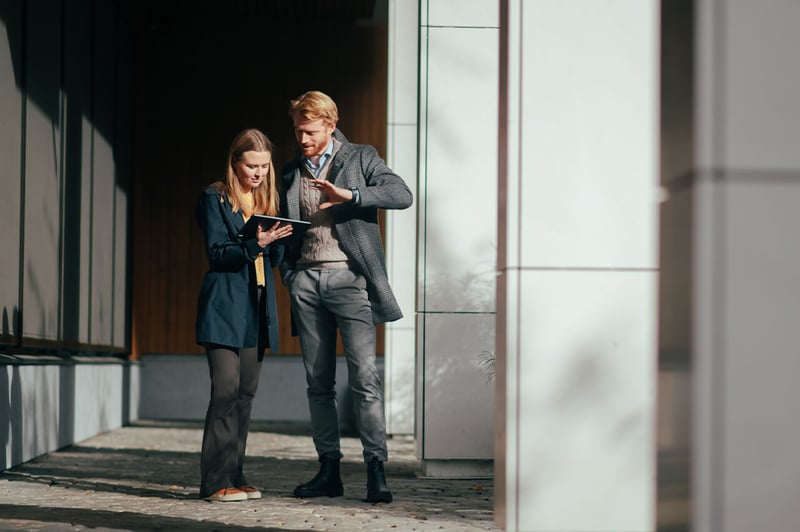 To personer står og ser på en ipad ute