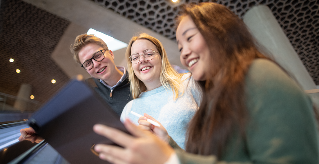 Three people smiling and looking at a screen