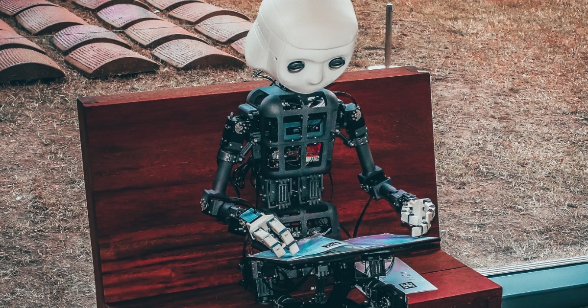 Robot som sitter og ser ned på en ipad
