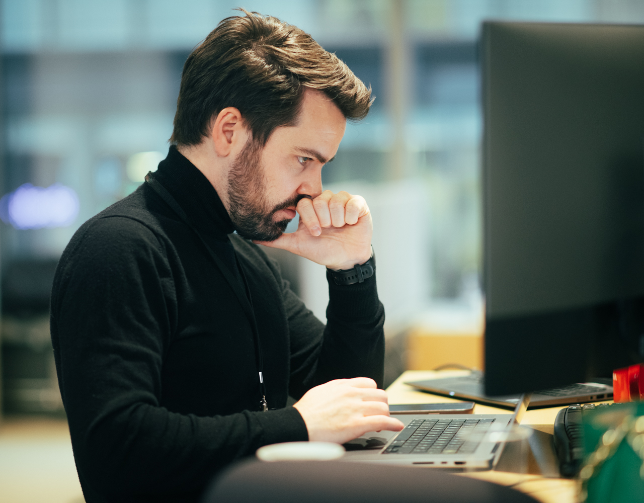 Mann sitter og ser på en PC-skjerm