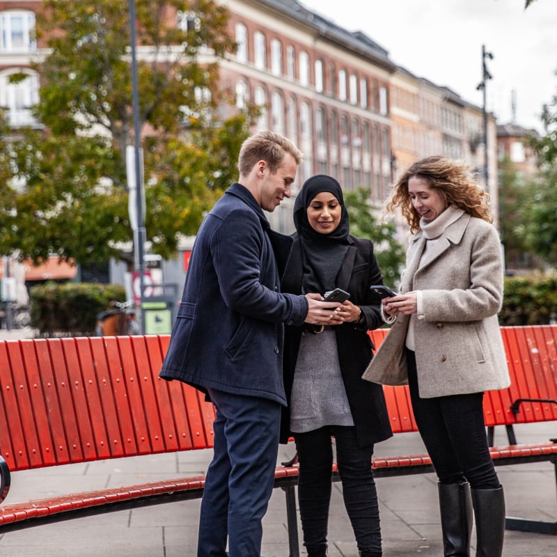 Folk henger utendørs, mens de viser hverandre innhold på mobilene sine